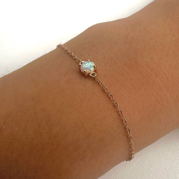 The Sardinia Bracelet by LLUME Jewelry features a delicate gold plated sterling silver chain and a small iridescent blue opal stone—an adjustable, dainty accessory that adds elegant sparkle to any occasion.