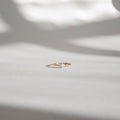 The Sardinia Ring by LLUME Jewelry, a delicate 14k gold filled opal ring, rests on a softly lit white surface with blurred shadows in the background.