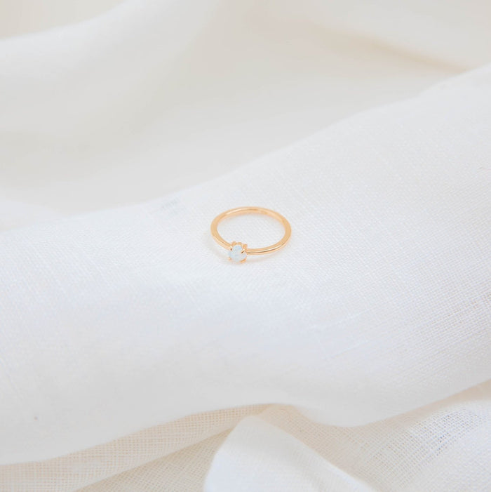 The Sardinia Ring by LLUME Jewelry, crafted in 14k gold fill with an opal, rests on soft white fabric for a minimal and elegant look.