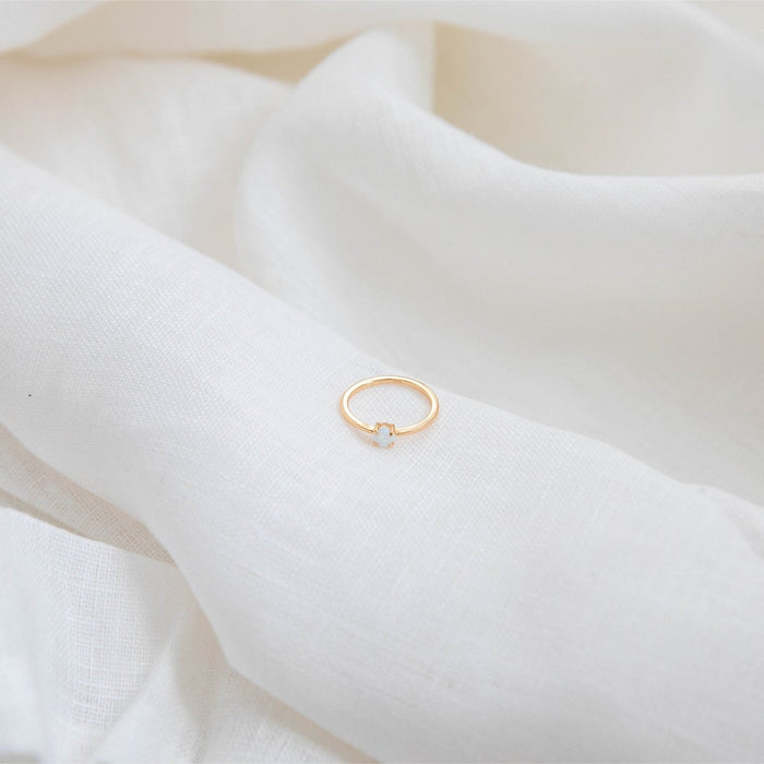 The Sardinia Ring by LLUME Jewelry, crafted in delicate 14k gold fill and set with opal, rests on gently folded soft white fabric.