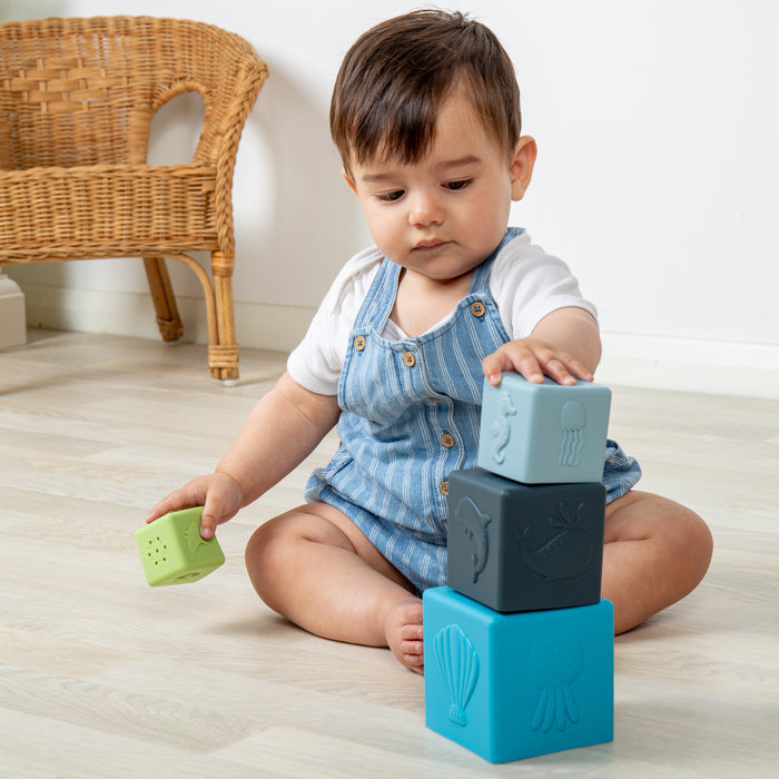 Child playing with colorful blocks on a light wooden floor.