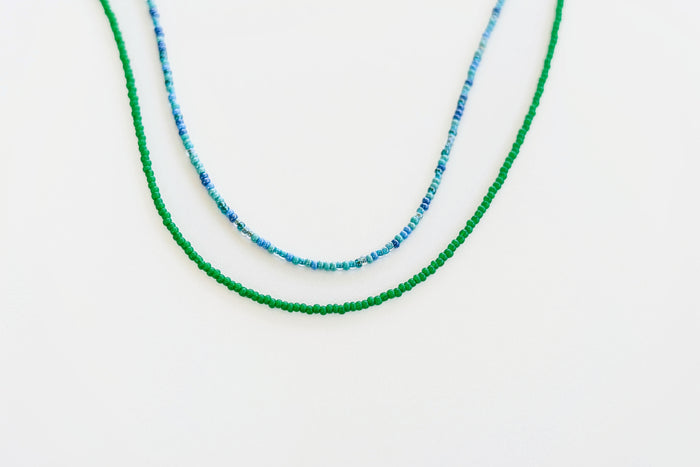Two Searidge Mini Beaded Necklaces from LLUME Jewelry are shown on a white background—one is solid green, and the other combines blue and white seed beads. This handmade set adds vibrant color to your style.