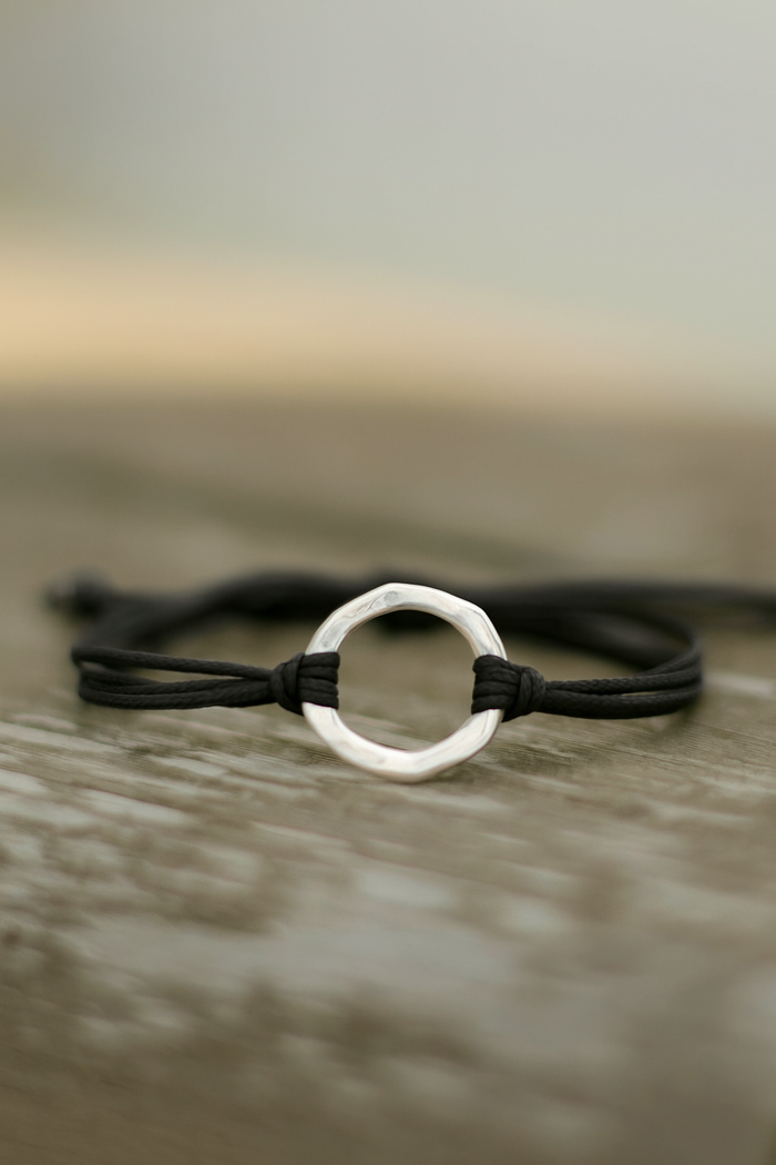 Bracelet with a silver circular clasp on a wooden surface