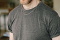 A man wearing a silver link chain necklace with a clasp closure.