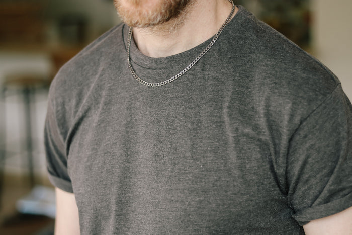 A man wearing a silver link chain necklace with a clasp closure.