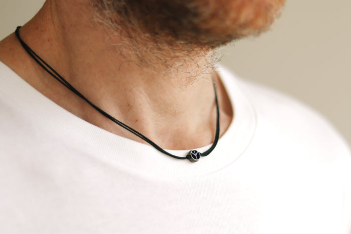 Person wearing a peace black necklace with a blurred background