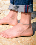 Man wearing a silver chain anklet on a rocky surface
