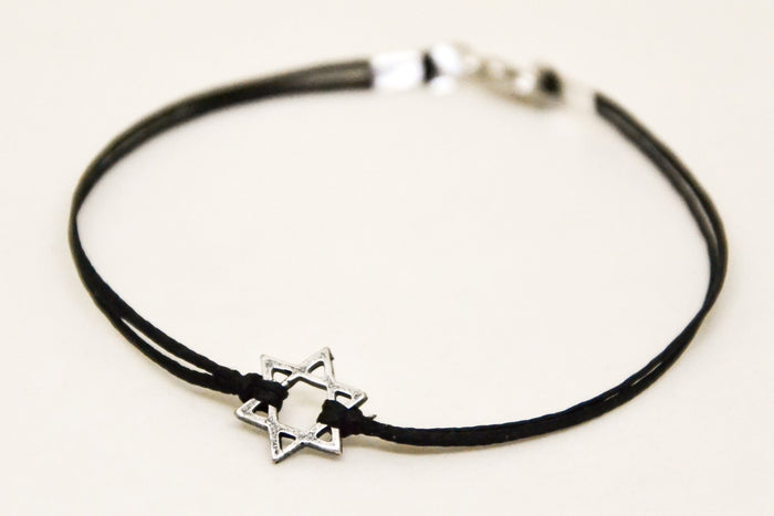 Black cord bracelet with a silver star charm on a white background