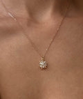 A close-up of the LLUME Jewelry Snowflake Necklace, featuring a gold filled chain and a delicate sunburst pendant with sparkling stones—perfect holiday jewelry, elegantly draped around the neck with bare shoulders.