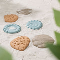 Set of colorful tactile toys on a sandy surface.