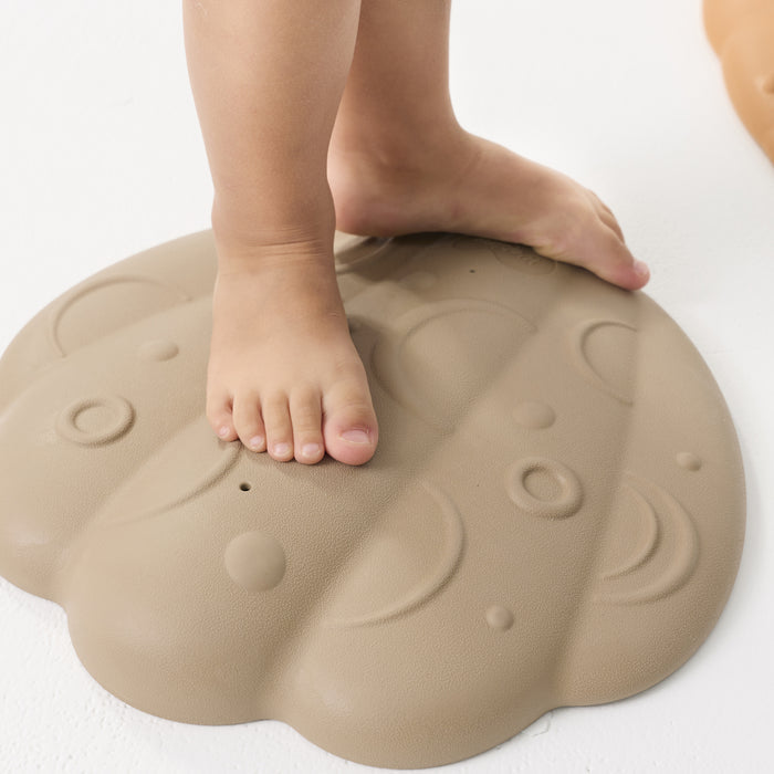 Child's feet on a beige tactile shell with a white background