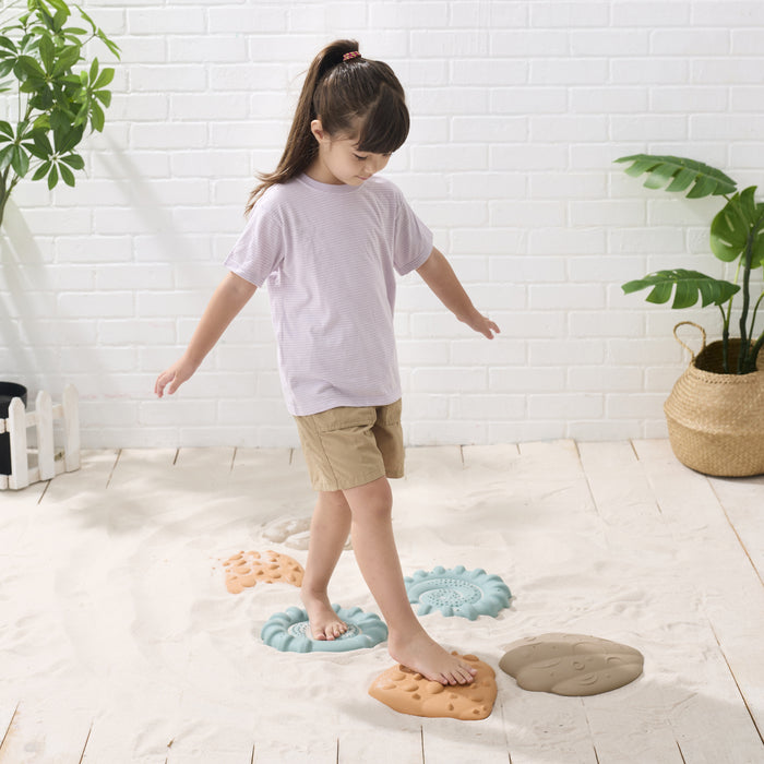 Child standing on a set of colorful stepping stones in a home setting.