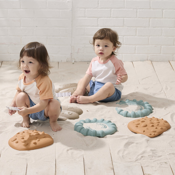 Two children playing with toy shells on a wooden floor.