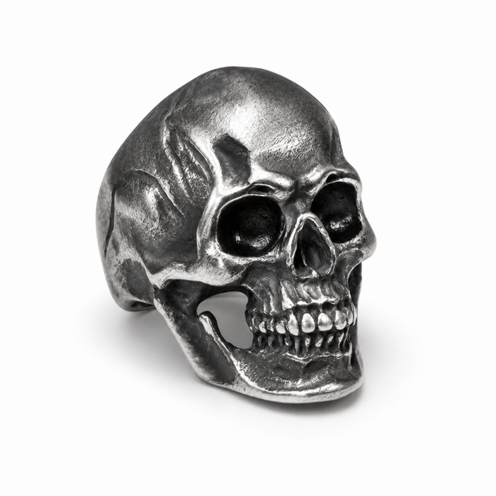 Front view of a stainless steel skull ring with a detailed vintage finish on a white background.