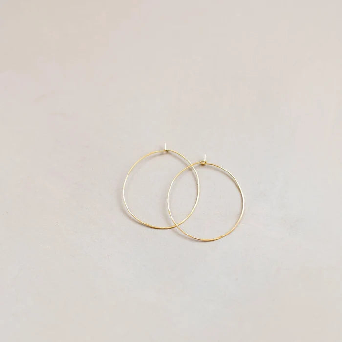 The Summer Shine Set by LLUME Jewelry features two thin gold hoop earrings, perfect for summer stacking, displayed overlapping on a light, neutral surface.
