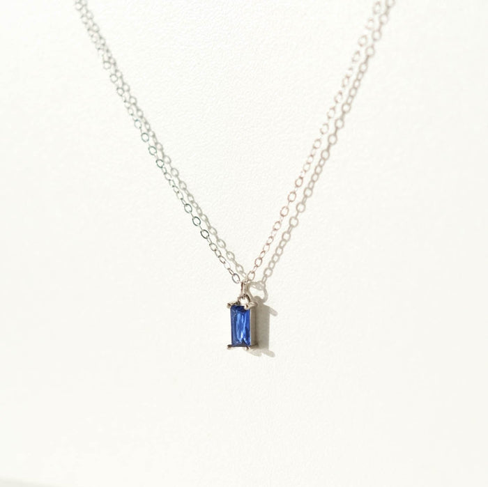 The Taylor Necklace Silver by LLUME Jewelry is a delicate sterling silver piece with a small rectangular sapphire blue charm pendant, shown against a plain white background.