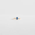 The Taylor Ring by LLUME Jewelry features a 14k gold-filled band with a rectangular blue sapphire, displayed on a plain light gray background.
