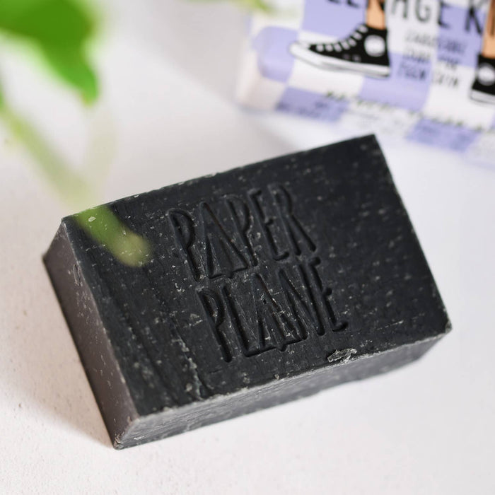 Paper Plane charcoal soap bar with embossed logo on light surface