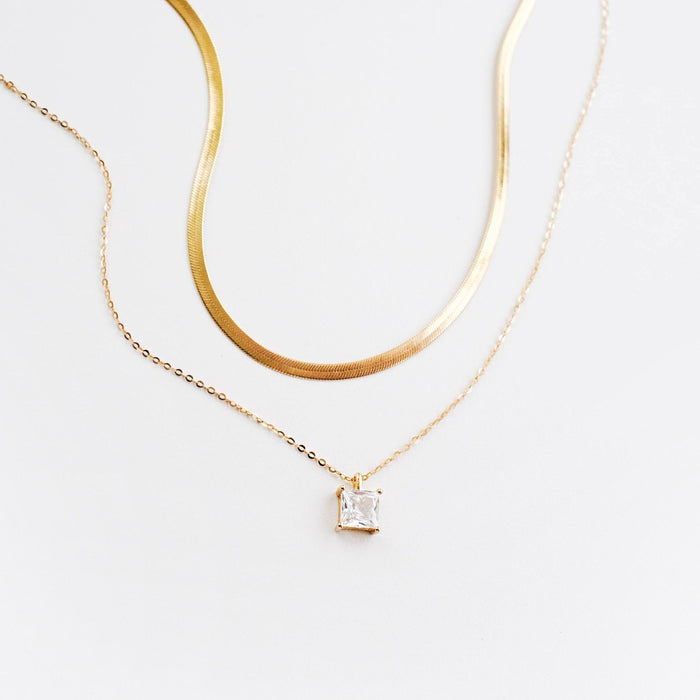 Two delicate LLUME Jewelry necklaces on a white background: The Classic Set (retired), featuring fine chains and a square-cut clear gemstone pendant—a stunning set perfect for layering.