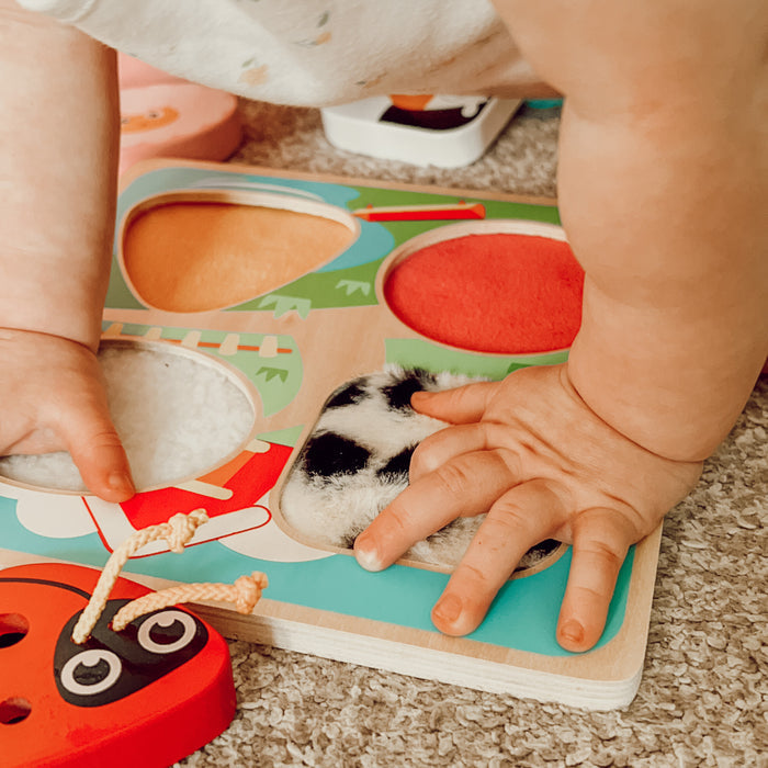 Child playing with a colorful wooden puzzle toy on a carpeted floor.