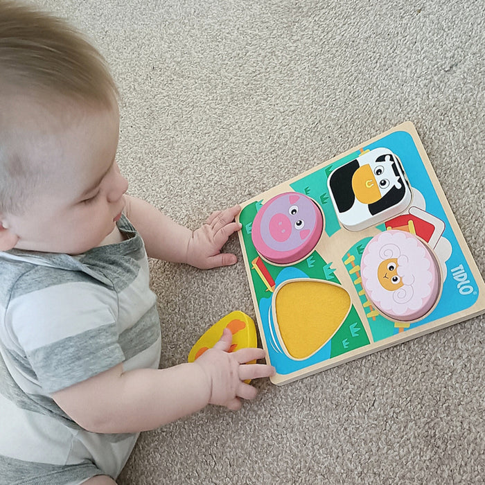 Baby playing with a colorful puzzle toy on a carpeted floor