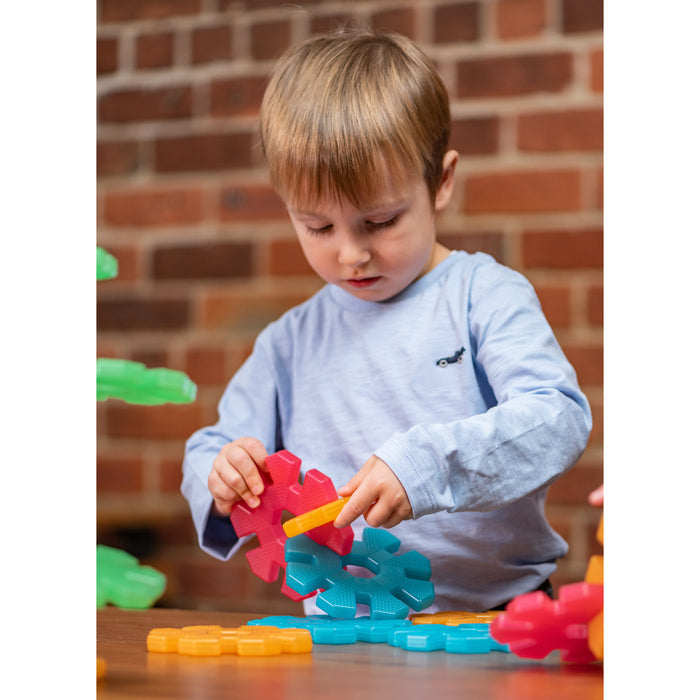 Child playing with colorful building blocks against a brick wall.