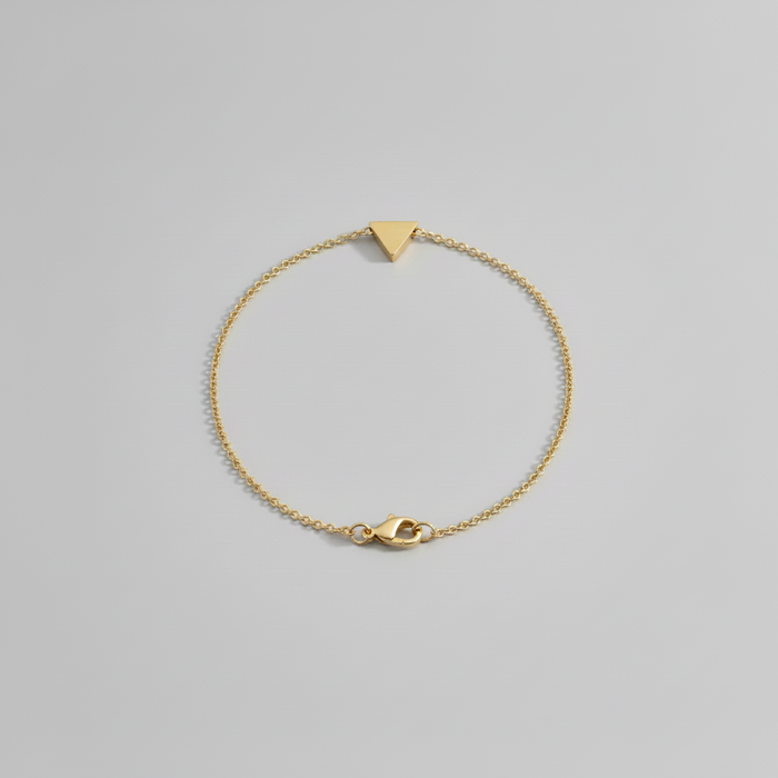 Gold bracelet with a triangle-shaped clasp on a light gray background