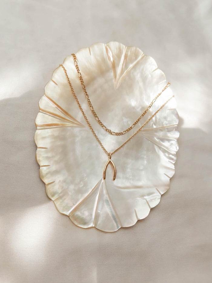 The LLUME Jewelry Wishbone Daily Set is showcased on a glimmering, scalloped mother-of-pearl dish against a soft, light backdrop.